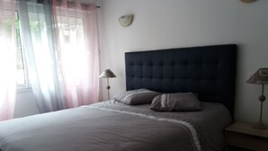 A bedroom with a large bed, two bedside lamps, and a window with curtains. - NANOU residence (Mont-Dore)