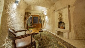 A room with a stone ceiling, a wooden chair, a table, and a fireplace. - Ages in Cappadocia (Nevsehir)