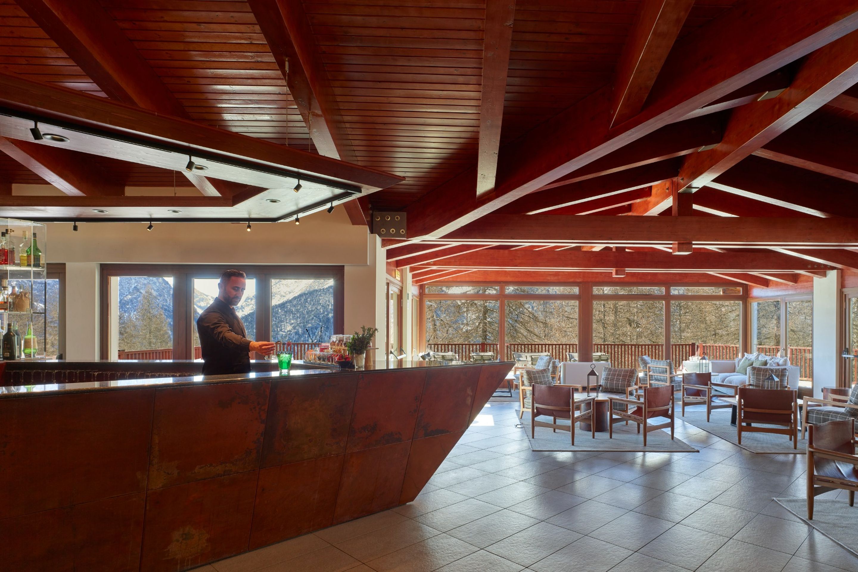 A spacious indoor area with a bar counter, seating area, and large windows offering views of the outdoors.