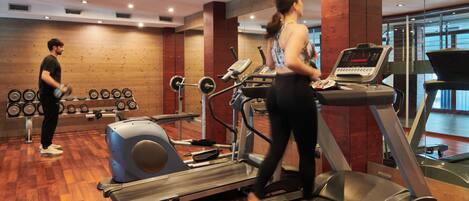 A gym with treadmills, a weight bench, and free weights.