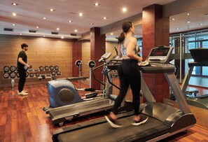 Un gimnasio con cintas de correr, un banco de pesas y pesas sueltas.