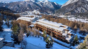 A large hotel with multiple floors and balconies, surrounded by snow-covered mountains and trees. - Hotel Sansicario Majestic (Cesana Torinese)