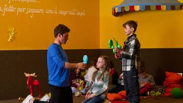 A group of people engaged in an activity with balloons and a wall with text in a room with a yellow wall and a red carpet.