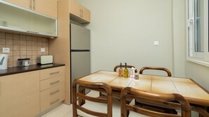 Cocina compacta con armarios de madera, refrigerador empotrado, mesa de comedor con sillas y ventana con vistas.