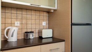 Una cocina con diseño moderno, que incluye un refrigerador de acero inoxidable, una tostadora blanca, un hervidor blanco y dos frascos de especias etiquetados como 'Café' y 'Azúcar'.