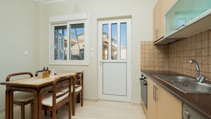 Cocina compacta con lavamanos, armarios y ventana con vista a una zona residencial.