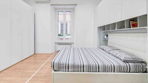 Une chambre à coucher avec un lit, une fenêtre et des étagères intégrées.