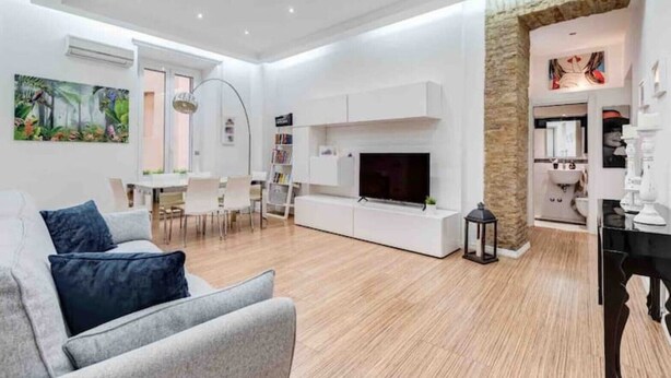 Un salon moderne doté d’un téléviseur à écran plat, d’une cheminée et d’un coin repas avec une table et des chaises.
