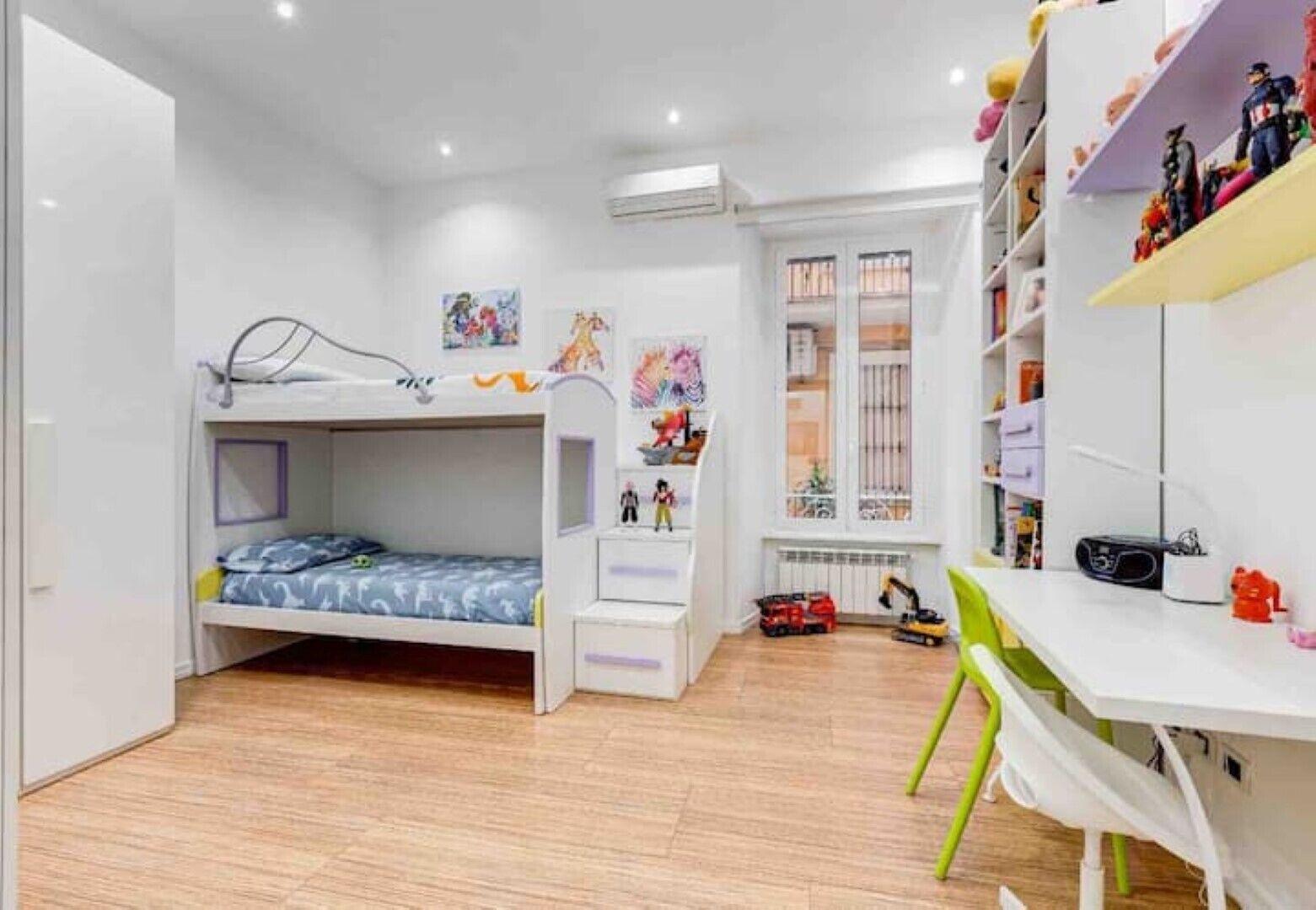 A child's bedroom with bunk beds, a desk, and toys.