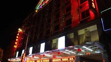 Un edificio con varios pisos, amplias ventanas y letreros iluminados.