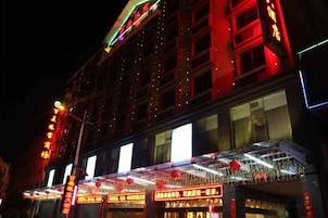 Un edificio con varios pisos, amplias ventanas y letreros iluminados.