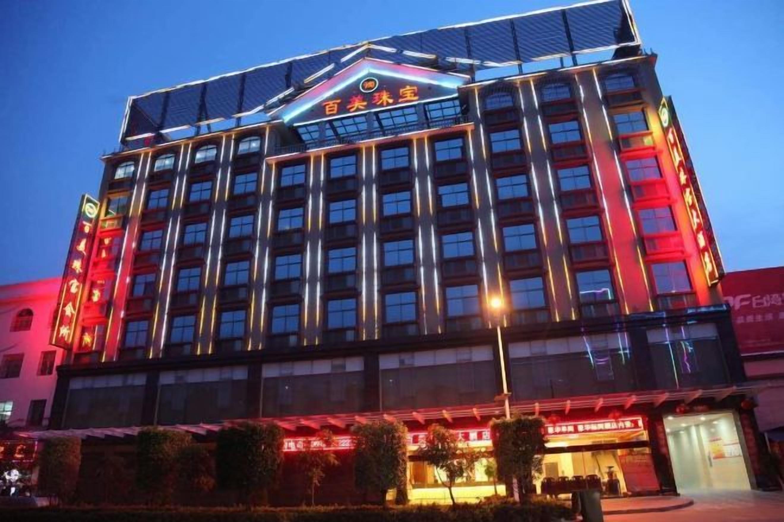 Un hotel de varios pisos con un letrero llamativo en la parte superior, múltiples ventanas y una fachada bien iluminada.