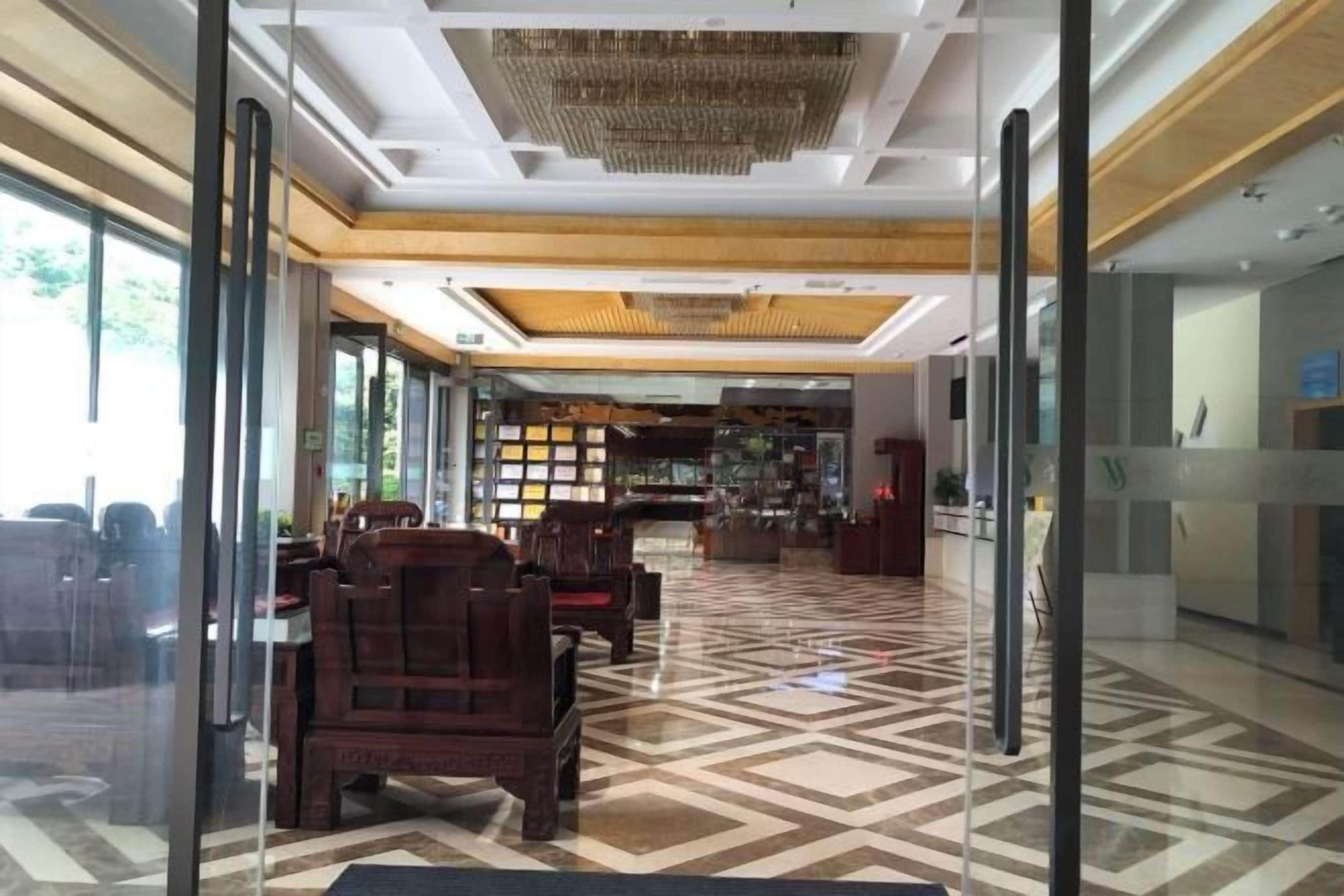 A hotel lobby with a check-in counter, seating area, and a patterned floor.