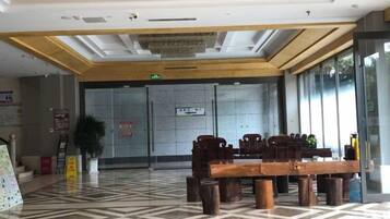 Un vestíbulo con mostrador de recepción, área de espera con mesas y sillas.