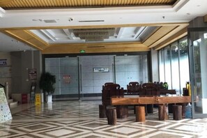 Eine Lobby mit Check-in-Schalter, Rezeption und einer Sitzecke mit Tischen und Stühlen.