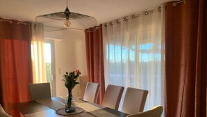 Un comedor con una mesa rectangular, seis sillas, un jarrón con flores y un ventilador de techo.