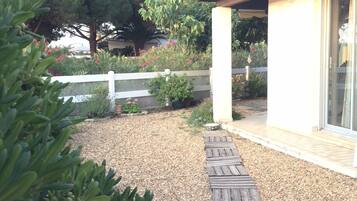 Stroll through the beautifully maintained garden, surrounded by lush plants and trees, and access the wooden deck via the gravel pathway.