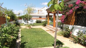 Un giardino curato con prato, un piccolo albero e piante fiorite.