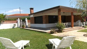 Una casa con un patio arredato con due sedie bianche e un tavolo.
