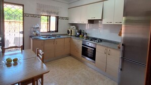 Una cucina con mobili in legno, frigorifero in acciaio inossidabile, piano cottura a gas e lavastoviglie.