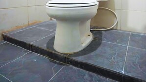 A toilet in a bathroom with white tiled walls and a dark tiled floor.