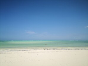 Na praia, areia branca, espreguiçadeiras, guarda-sóis 