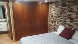 Un dormitorio con cama, armario de madera y pared con diseño de piedra.
