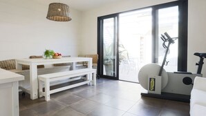 Ein modernes Wohnzimmer mit Esstisch, einer Bank und einem stationären Heimtrainer.