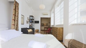 Ein Hotelzimmer mit einem großen Bett, einem Schreibtisch, einem Sessel, einem Fernseher und einer Küchenzeile.
