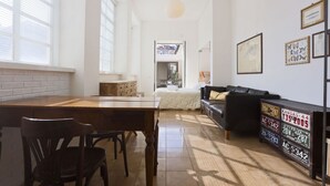 Ein geräumiger Wohnbereich mit Esstisch, Stühlen, einem schwarzen Sofa und einer Wand mit gerahmten Kunstwerken.
