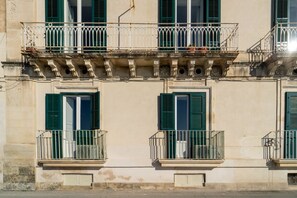 A building with multiple balconies, green shutters, and a classic architectural style. - GuestHost - Modern 120 sqm apartment with sea view, finely furnished, for up to 4 people, located on the ground floor of a building (a few steps to access it). The accommodation is located in the heart of Ortigia, the marvelous historic center of Syracus (Siracusa)