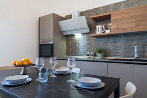 Uma cozinha moderna com uma mesa de jantar posta para quatro pessoas, uma fruteira e um vaso com planta.