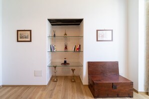A room with a wooden floor, a glass display cabinet with decorative items, and a wooden chest. - GuestHost - Modern 120 sqm apartment with sea view, finely furnished, for up to 4 people, located on the ground floor of a building (a few steps to access it). The accommodation is located in the heart of Ortigia, the marvelous historic center of Syracus (Siracusa)