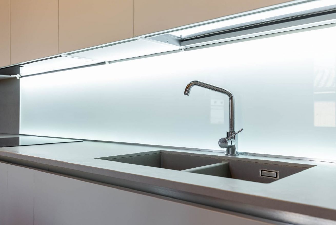 Una cucina moderna con lavello in acciaio inossidabile, un rubinetto e un piano di lavoro.