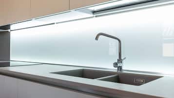 Una cucina moderna con lavello in acciaio inossidabile, un rubinetto e un piano di lavoro.