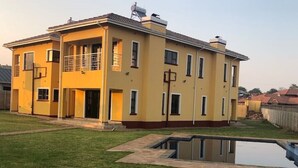 A two-story residential building with a flat roof, a small attached garage, and a swimming pool in the backyard. - Pomona BB House in Pomona Harare 7 Suites Executive &  Group Options  Best Value (Harare Harare)