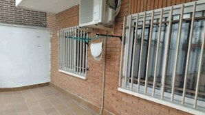 Une pièce d’angle avec un sol carrelé, un mur en briques et des fenêtres grillagées.