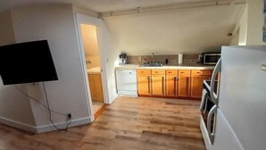 A compact kitchen with wooden cabinets, a white refrigerator, and a microwave. - A bedroom balcony with a view to the Ocean.  7 min walk to the beach (Old Orchard Beach)