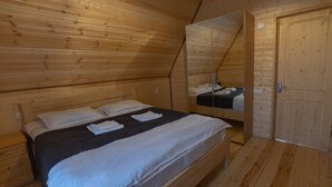 Camera da letto in una baita di legno, con un letto, uno specchio e una porta.