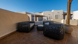 A rooftop terrace with wicker furniture and a view of neighboring buildings. - Peñon Blanco       . (Níjar)