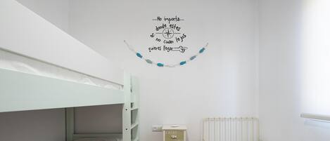 A bedroom with bunk beds, a small cabinet, and a wall decoration.