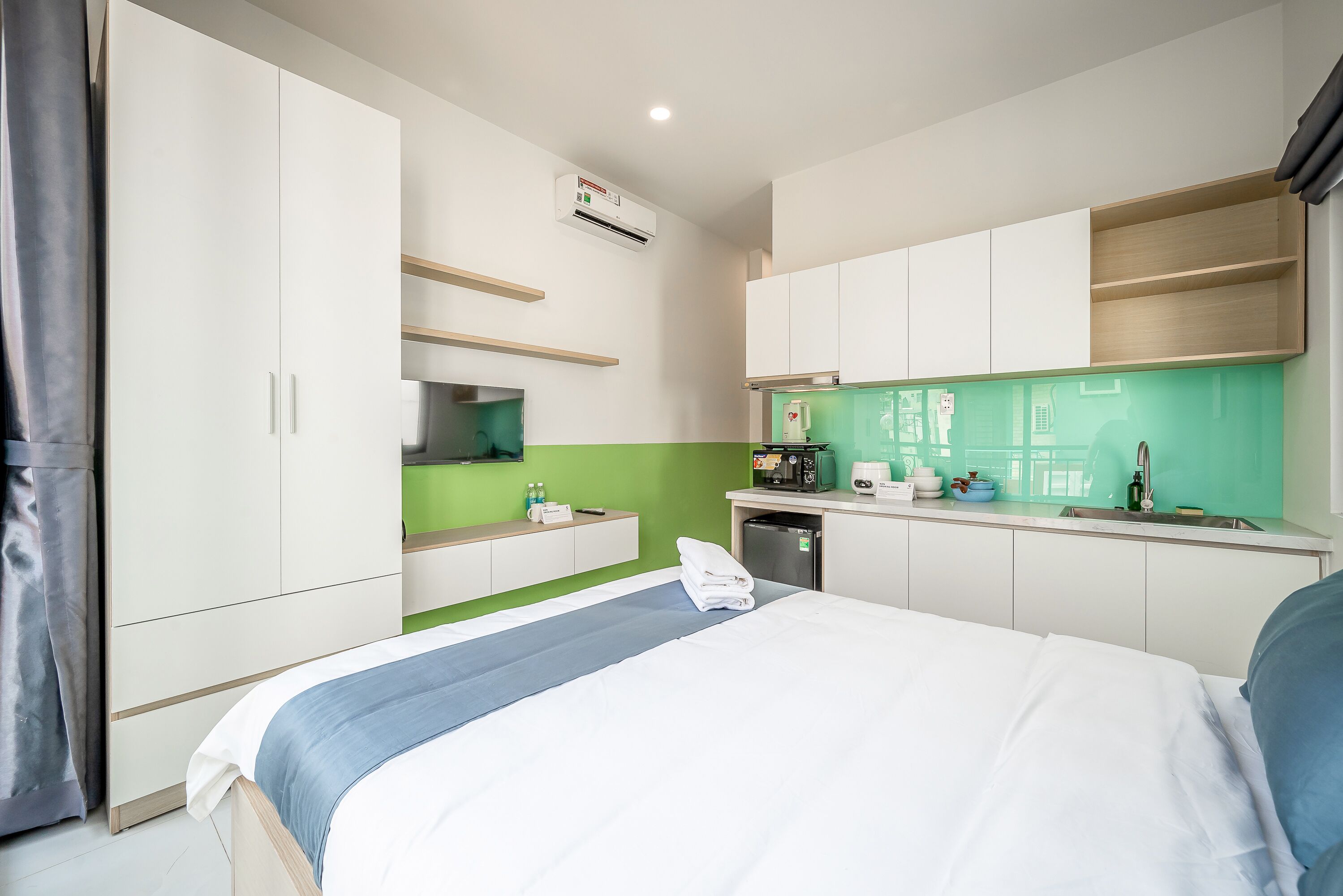 Une chambre d’hôtel moderne équipée d’un lit, d’une kitchenette et d’une salle de bain.
