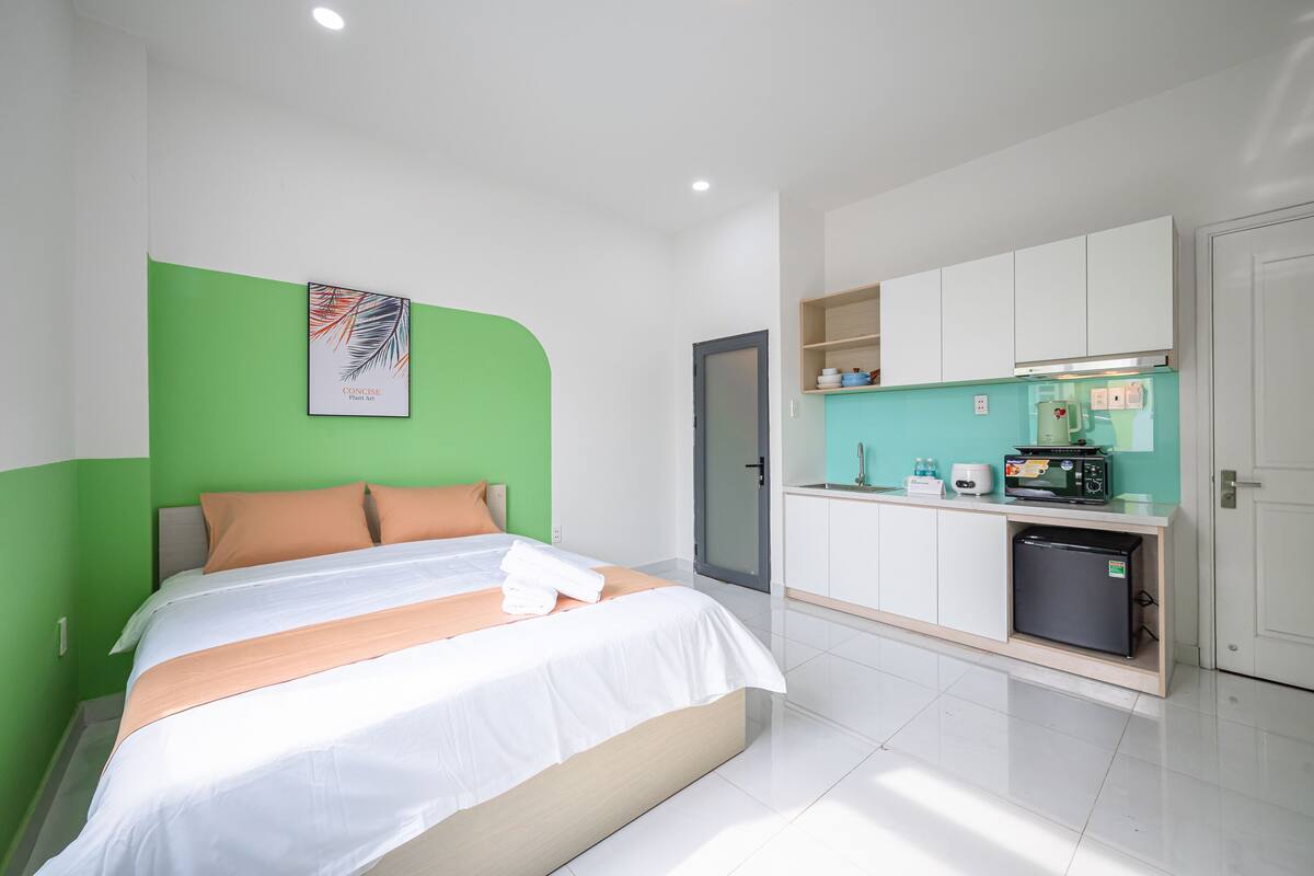 Ein modernes Hotelzimmer mit einem Bett, einer Küchenzeile und einer Wand in Grünton.