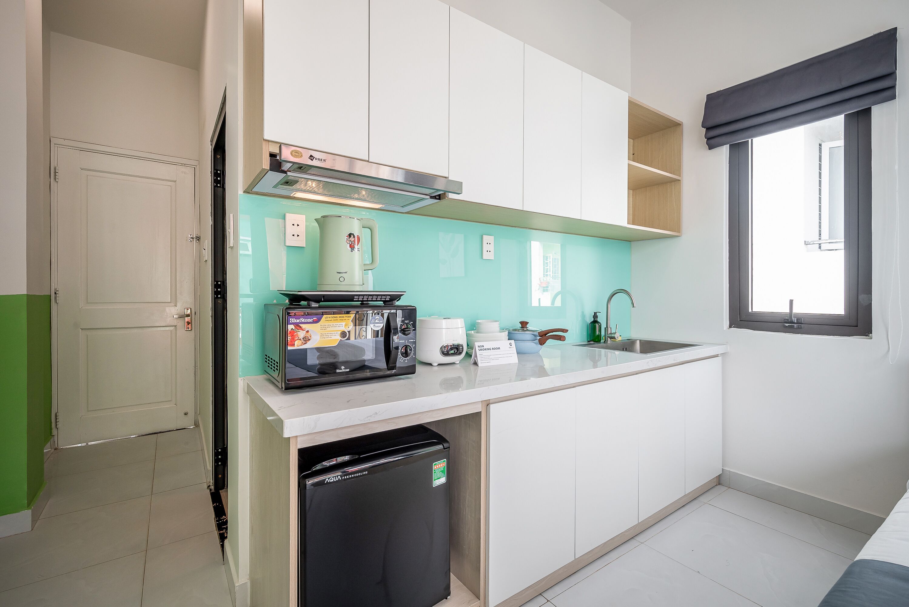 Een kleine keuken met een magnetron, koffiezetapparaat en een vaatwasser.