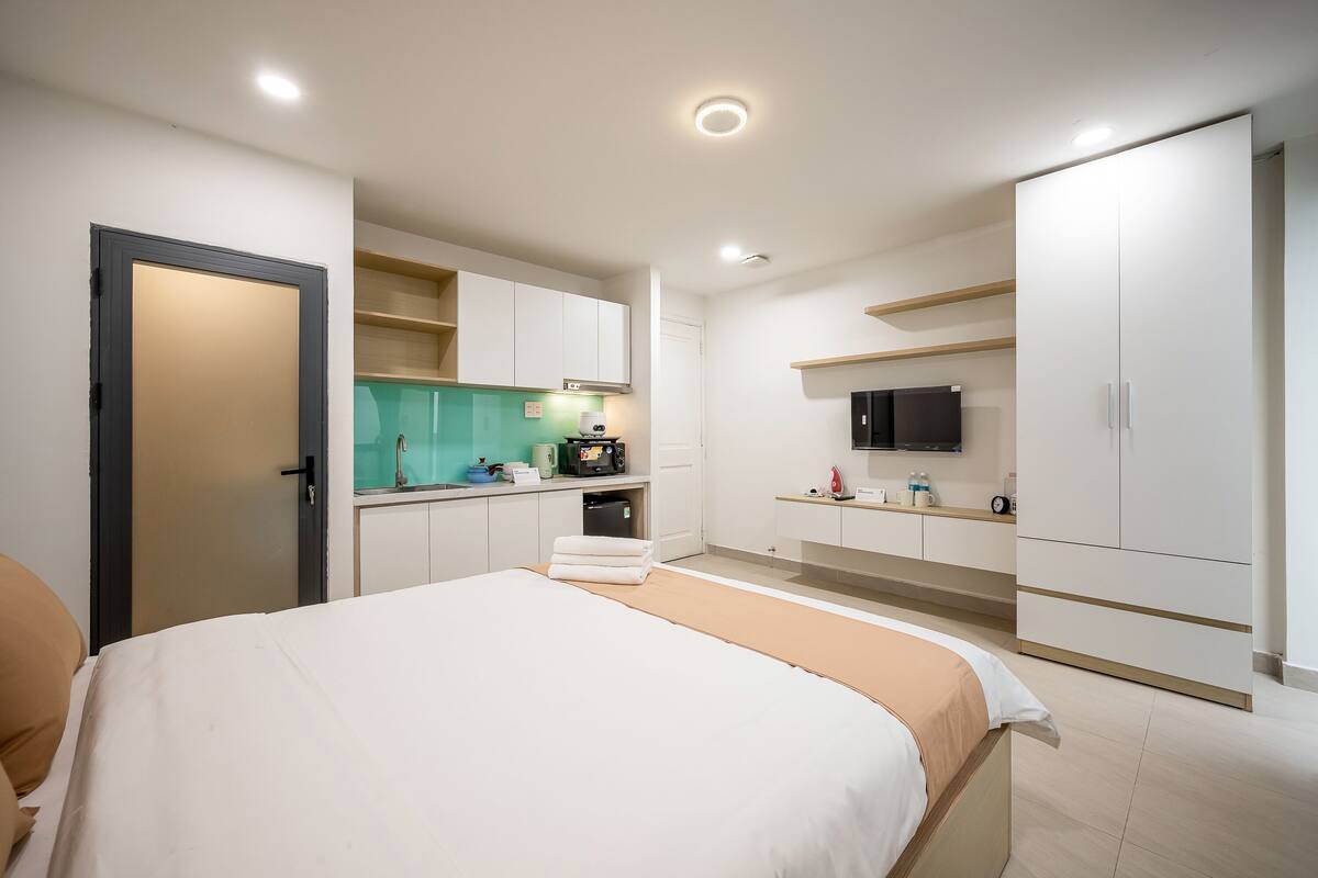 Ein modernes Hotelzimmer mit Bett, Küchenzeile und Fernseher.