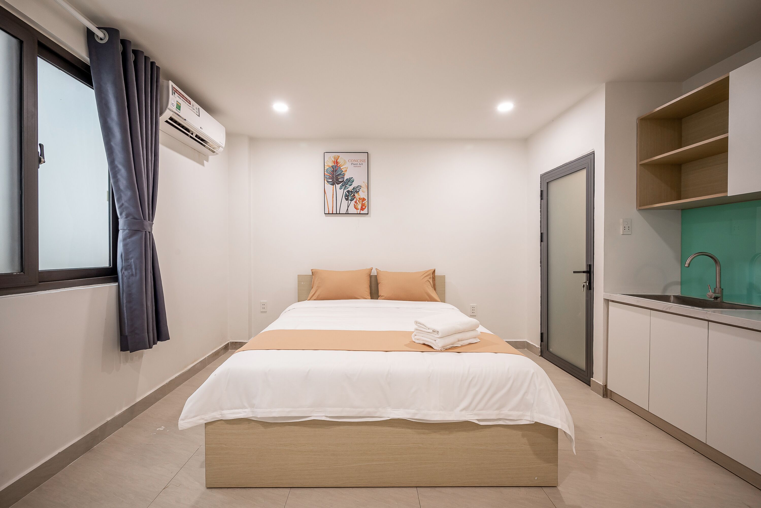 Un dormitorio con cama, ventana con cortinas, aire acondicionado, un cuadro, un lavamanos y un armario.