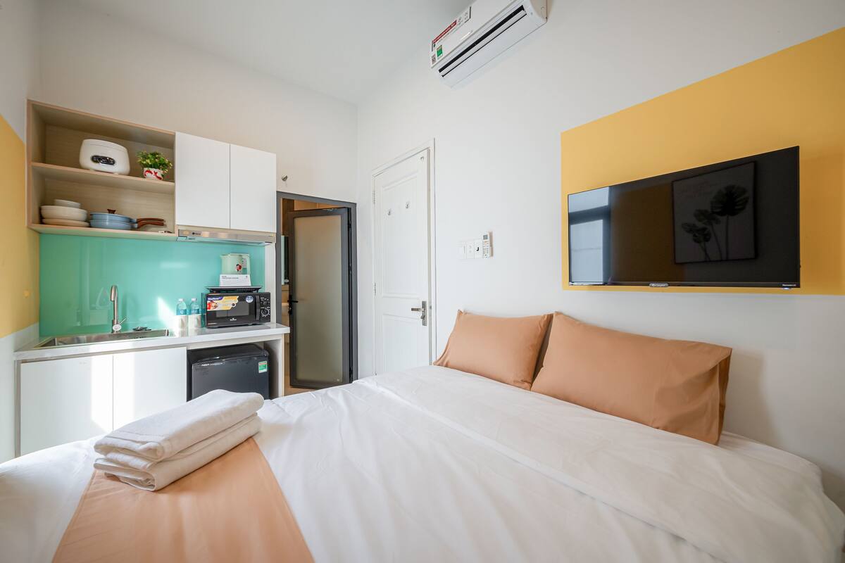 Ein Hotelzimmer mit einem Bett, einer Küchenzeile, einem Fernseher und einer Tür.