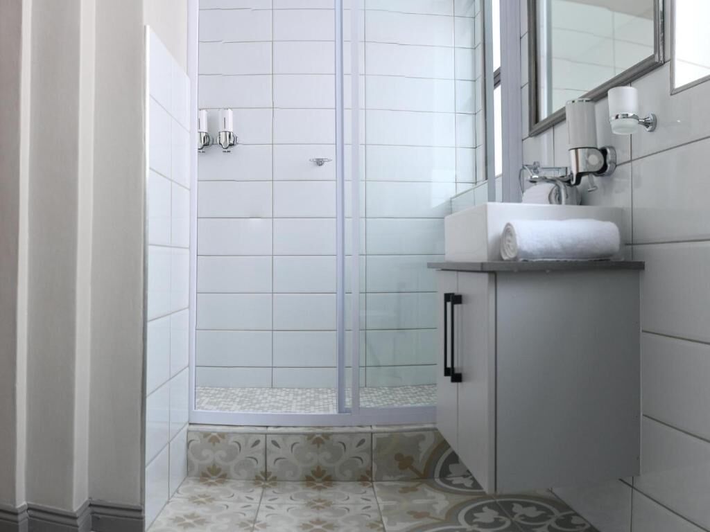A bathroom with a glass shower enclosure, a sink with a towel, and a mirror.