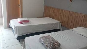 Habitación de hotel con dos camas, cabecero de madera, aire acondicionado de pared y una puerta.
