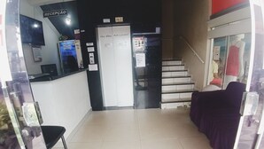 Uma área de recepção com balcão, escada e um manequim em uma vitrine.